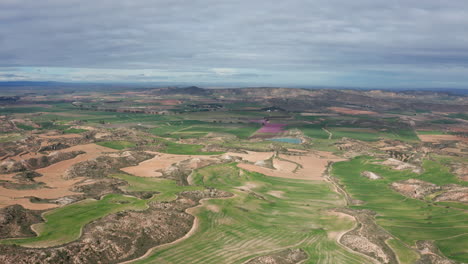 Vista-Aérea-Del-Paisaje-Rural-España-Día-Nublado-Campos-Verdes-Y-Colinas-Rocosas